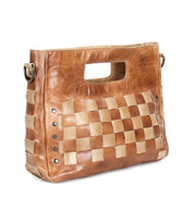 Introducing the Orchid by Bed|Stü: a handwoven brown leather handbag featuring woven beige accents, a rectangular cutout handle, and metal rivet details on the side—showcasing modern timeless design.