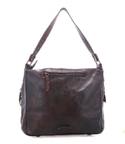 The Bed|Stü Packet LTC is a dark brown leather shoulder tote bag featuring a top handle, front zipper pocket, and visible edge stitching—ideal as a stylish travel tote for your daily adventures.
