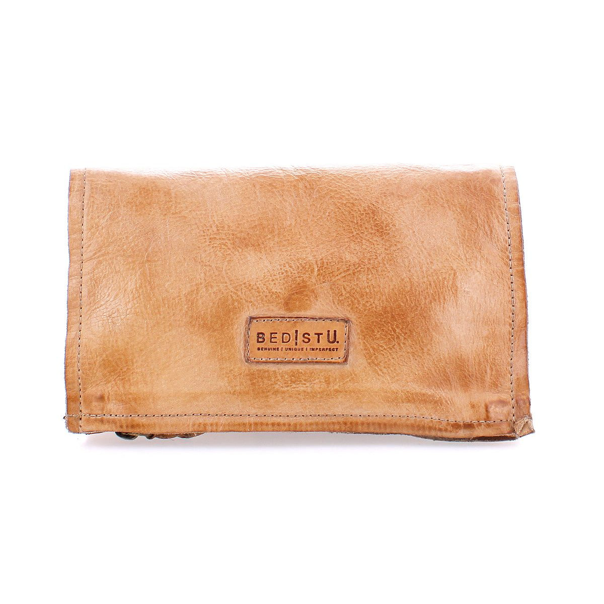 Parle by Bed|Stü is a tan leather wallet with visible stitching and a rectangular "BED|STÜ" branded label on the front, featuring zippered compartments to keep your essentials organized.
