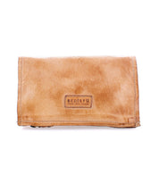 Parle by Bed|Stü is a tan leather wallet with visible stitching and a rectangular "BED|STÜ" branded label on the front, featuring zippered compartments to keep your essentials organized.