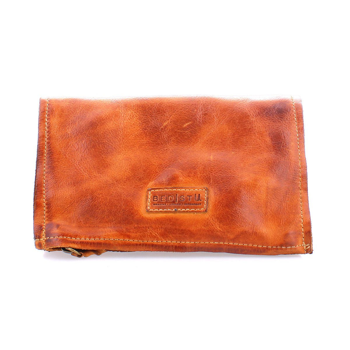 The Parle wallet by Bed|Stü is a brown leather accessory with visible stitching and a rectangular "Bed|Stü" logo patch on the front, photographed against a white background, featuring zippered compartments for secure storage.