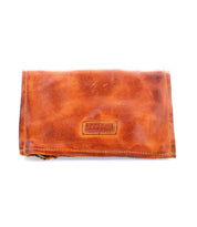 The Parle wallet by Bed|Stü is a brown leather accessory with visible stitching and a rectangular "Bed|Stü" logo patch on the front, photographed against a white background, featuring zippered compartments for secure storage.