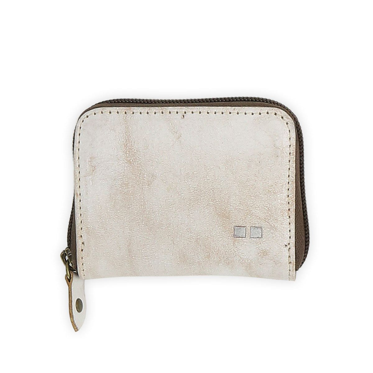 The Peek wallet by Bed|Stü is a small, rectangular beige zippered accessory crafted from premium leather, featuring a metal pull tab and two small square accents on the front. Inside, accordion card slots provide organized and convenient storage.