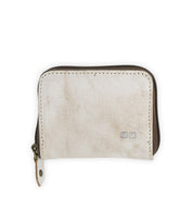 The Peek wallet by Bed|Stü is a small, rectangular beige zippered accessory crafted from premium leather, featuring a metal pull tab and two small square accents on the front. Inside, accordion card slots provide organized and convenient storage.