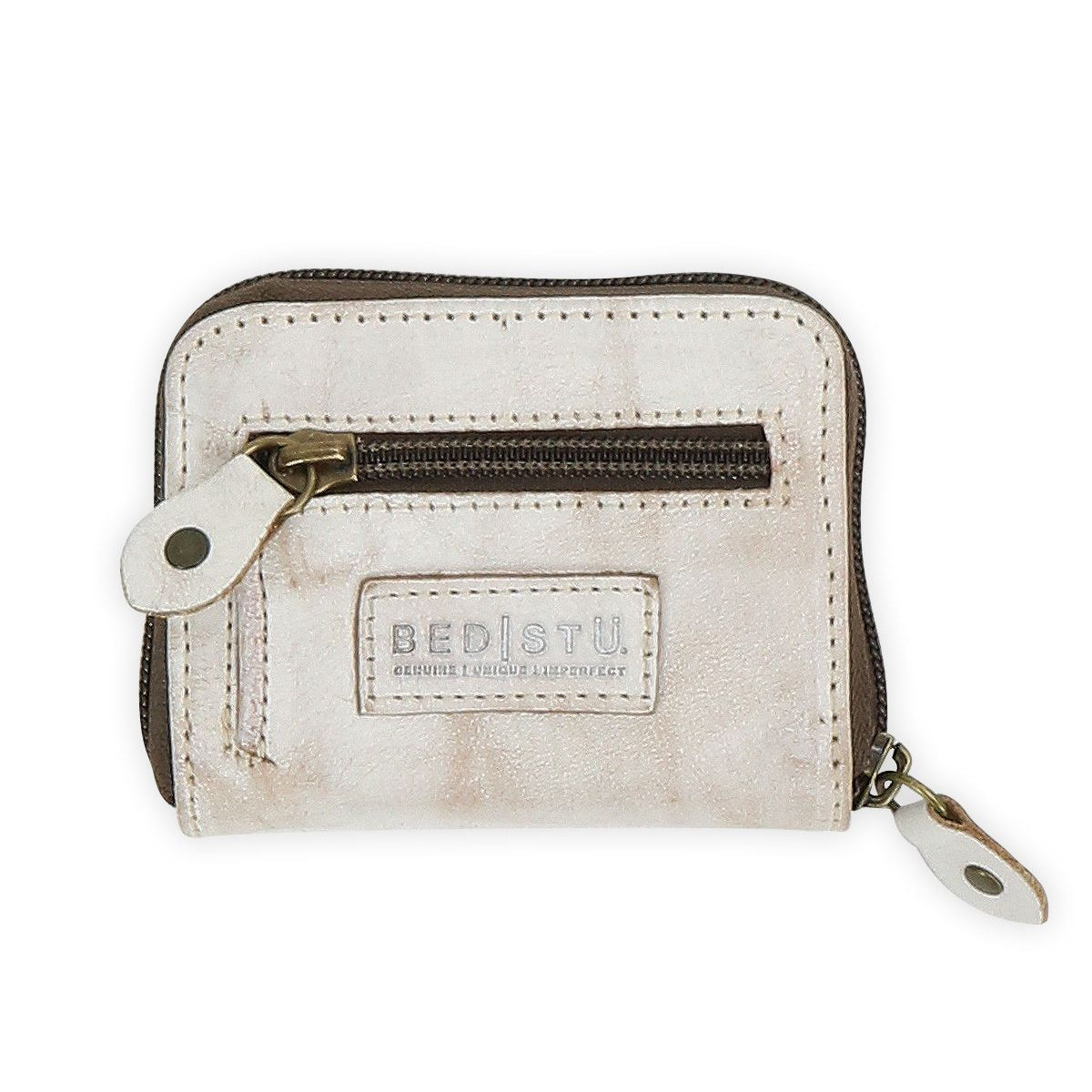 The Bed|Stü Peek is a small beige zippered wallet crafted from premium leather, featuring a front zipper pocket, dual zipper pulls, accordion-style card slots inside, and a Bed|Stü logo patch on the front.