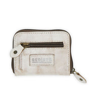 The Bed|Stü Peek is a small beige zippered wallet crafted from premium leather, featuring a front zipper pocket, dual zipper pulls, accordion-style card slots inside, and a Bed|Stü logo patch on the front.