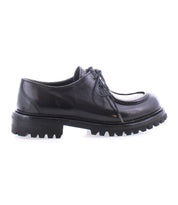 The Portare by Bed|Stü is a black leather lace-up dress shoe, shown in profile against a white background, featuring a chunky, ridged rubber sole and subtle moc-toe detailing reminiscent of vintage-inspired boots.