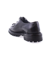 The Bed|Stü Portare, a black leather dress shoe with a thick, rugged sole, is displayed from a rear angle on a white background, merging classic sophistication with the robust charm of vintage-inspired boots.