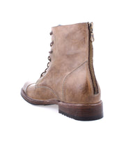The Bed|Stü Protege is a brown leather lace-up combat boot featuring a back zipper, shown from the rear left side against a white background. Crafted with Goodyear welt construction, these durable boots offer lasting performance and style.