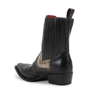 The Bed|Stü Raise is a black and beige Western short boot featuring a low heel, snip toe, decorative stitching, studded accents, and a pull tab at the back.