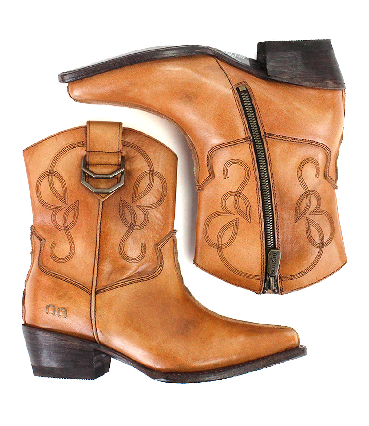 The Bed|Stü Rangeley is a pair of tan leather cowboy boots featuring a distinctive design with decorative stitching and lines, a side zipper with dual D-rings, chunky heel, and pointed toes. Shown from the side and top views on a white background.
