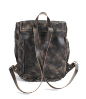 The Bed|Stü Ranger backpack is a sturdy, distressed dark brown leather accessory featuring adjustable shoulder straps, a top handle, and a vertical zippered side pocket, designed for everyday wear and displayed against a white background.