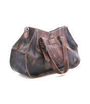 The Bed|Stü Redrock handbag, crafted from distressed brown leather, features a buckled handle, a front pocket, and a heritage-inspired design, showcased against a white background.