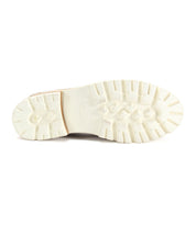 The image features the bottom view of a white rubber sole with a rugged, textured tread pattern, perfectly complementing the modern essential style of the Reina III penny loafer from Bed|Stü, which is crafted from hand-finished leather.
