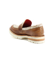 The Reina III by Bed|Stü is a brown and beige hand-finished leather penny loafer featuring a white chunky sole, exposed stitching, and a distinctive red interior lining—shown angled from the back, this elevated modern essential adds sophistication to any wardrobe.