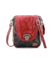 Introducing the Rhyme by Bed|Stü—a small, vintage-style leather crossbody bag featuring a striking red flap, classic black body, metal clasp, and adjustable strap. Shown against a white background, this bag offers hands-free convenience while bringing a retro touch of charm to any outfit.