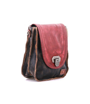 The Bed|Stü Rhyme is a small, vintage-inspired leather satchel featuring a worn brown body, a red flap, and a silver clasp, displayed against a white background—a charming crossbody bag that offers hands-free convenience for everyday use.