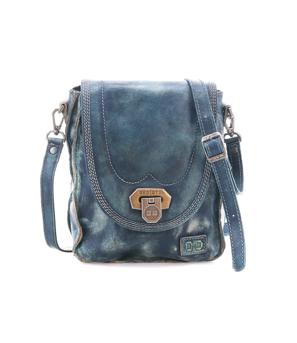 The Bed|Stü Rhyme is a small blue leather crossbody bag featuring a flap closure with metal clasp, adjustable strap, and visible stitching for added detail, offering hands-free convenience and shown against a white background.