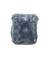 The Bed|Stü Rhyme, a dark blue leather crossbody bag featuring visible creases and a rectangular patch at the bottom center, is photographed against a white background and offers a stylish hands-free option for everyday carry.