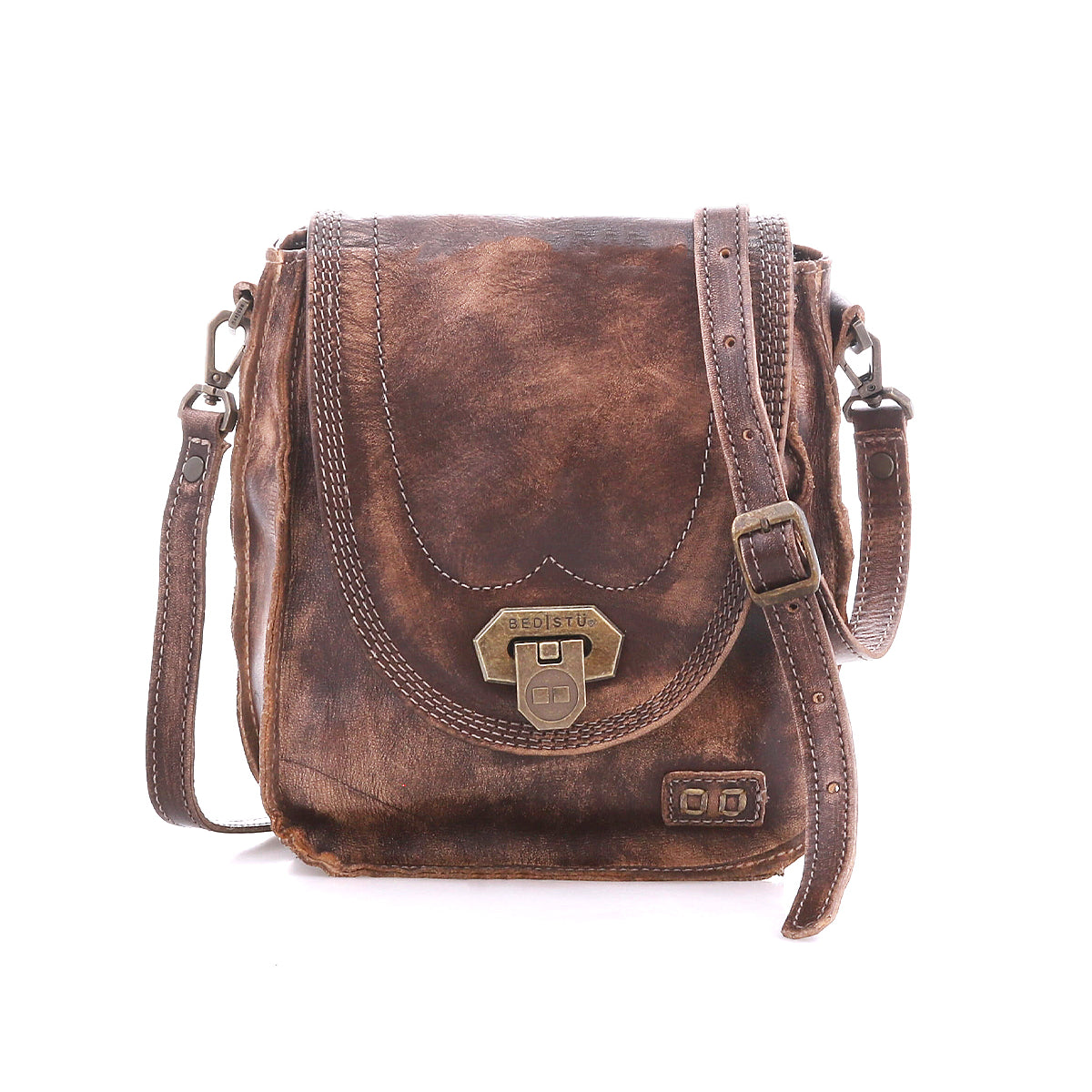 The Bed|Stü Rhyme is a brown leather crossbody bag with a vintage finish, featuring a metal clasp closure, adjustable strap for hands-free convenience, and decorative stitching, shown on a white background.