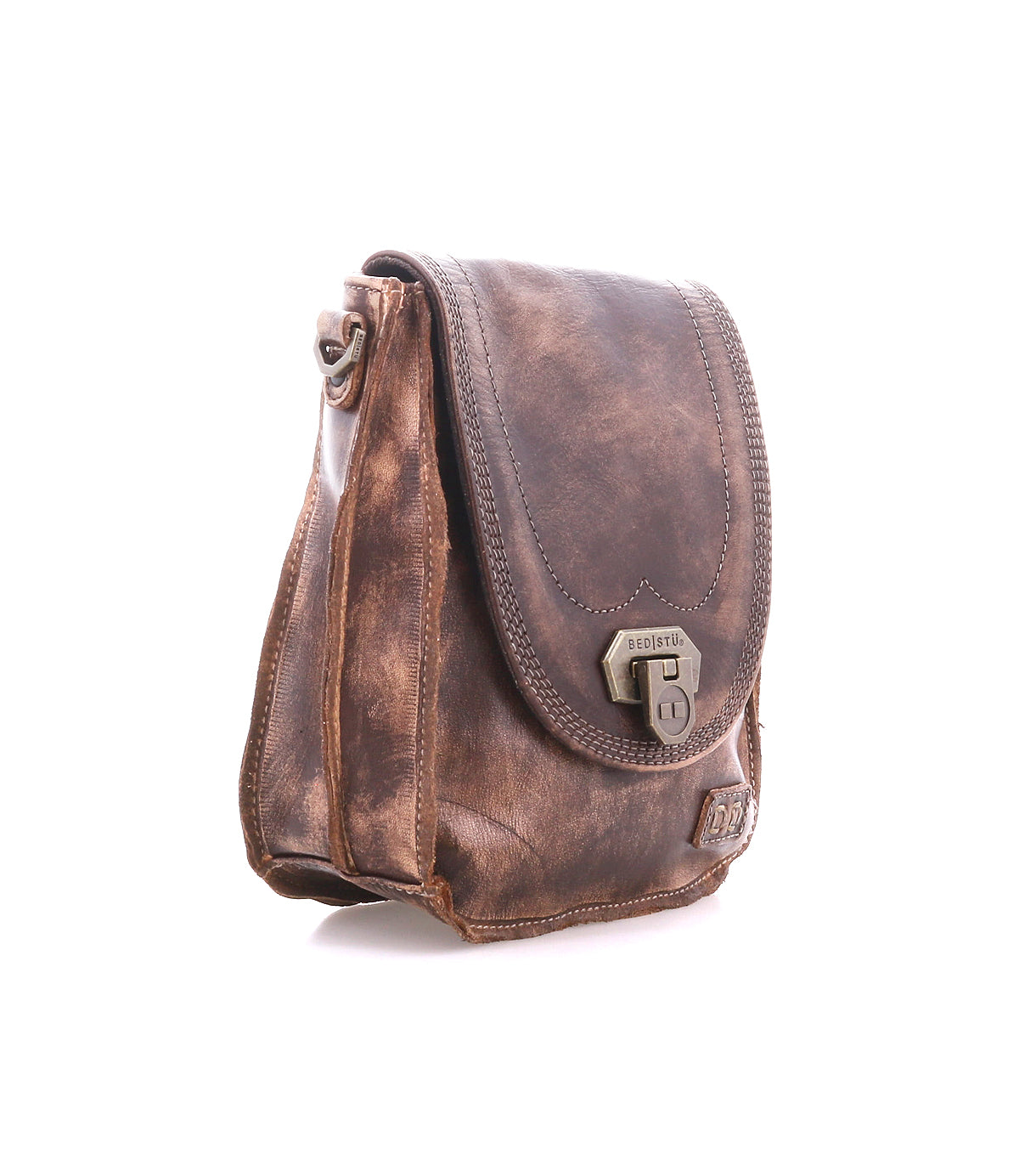 The Bed|Stü Rhyme crossbody bag, crafted in brown leather with a front flap, buckle closure, and visible stitching for a hands-free experience, is photographed on a white background.