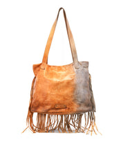 The Bed|Stü Rimes is a brown handcrafted leather tote with fringe detail along the sides and bottom, two handles, a spacious interior, and a small rectangular label on the front.