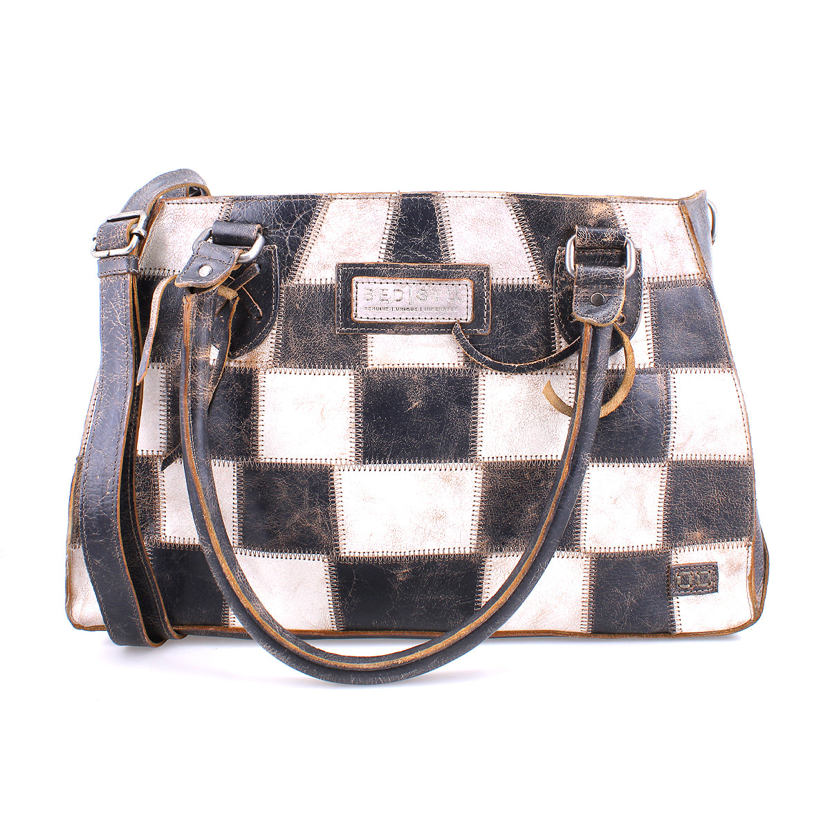The Bed|Stü Rockababy SL is a rectangular, sustainable handbag featuring a black and white checkerboard pattern, two handles, and an adjustable shoulder strap.