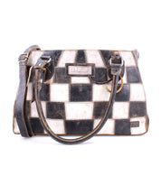The Bed|Stü Rockababy SL is a rectangular, sustainable handbag featuring a black and white checkerboard pattern, two handles, and an adjustable shoulder strap.