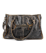 The Rockababy SL by Bed|Stü, an upcycled black leather bag with two handles, a front zipper pocket, and brown trim, is displayed against a white background.