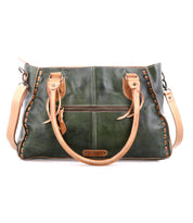 The Bed|Stü Rockababy handbag, crafted from green vegetable-tanned leather with tan handles and trim, features decorative stitching, a front zipper pocket, and a compact design. Shown against a white background.