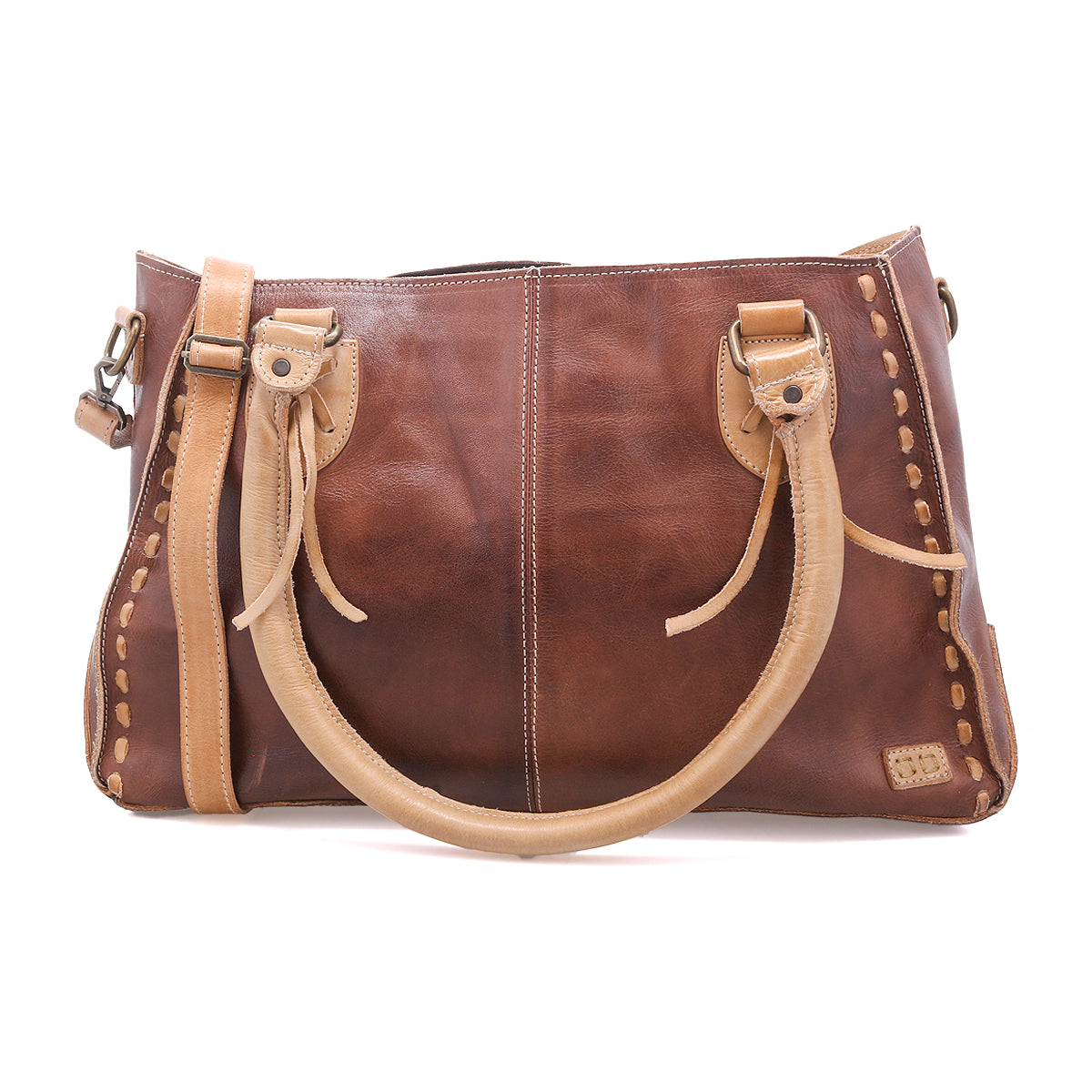 The Bed|Stü Rockababy is a compact brown leather handbag crafted from vegetable-tanned leather, featuring light tan handles and stitching, metal hardware, and a rectangular shape. The bag is photographed on a white background.