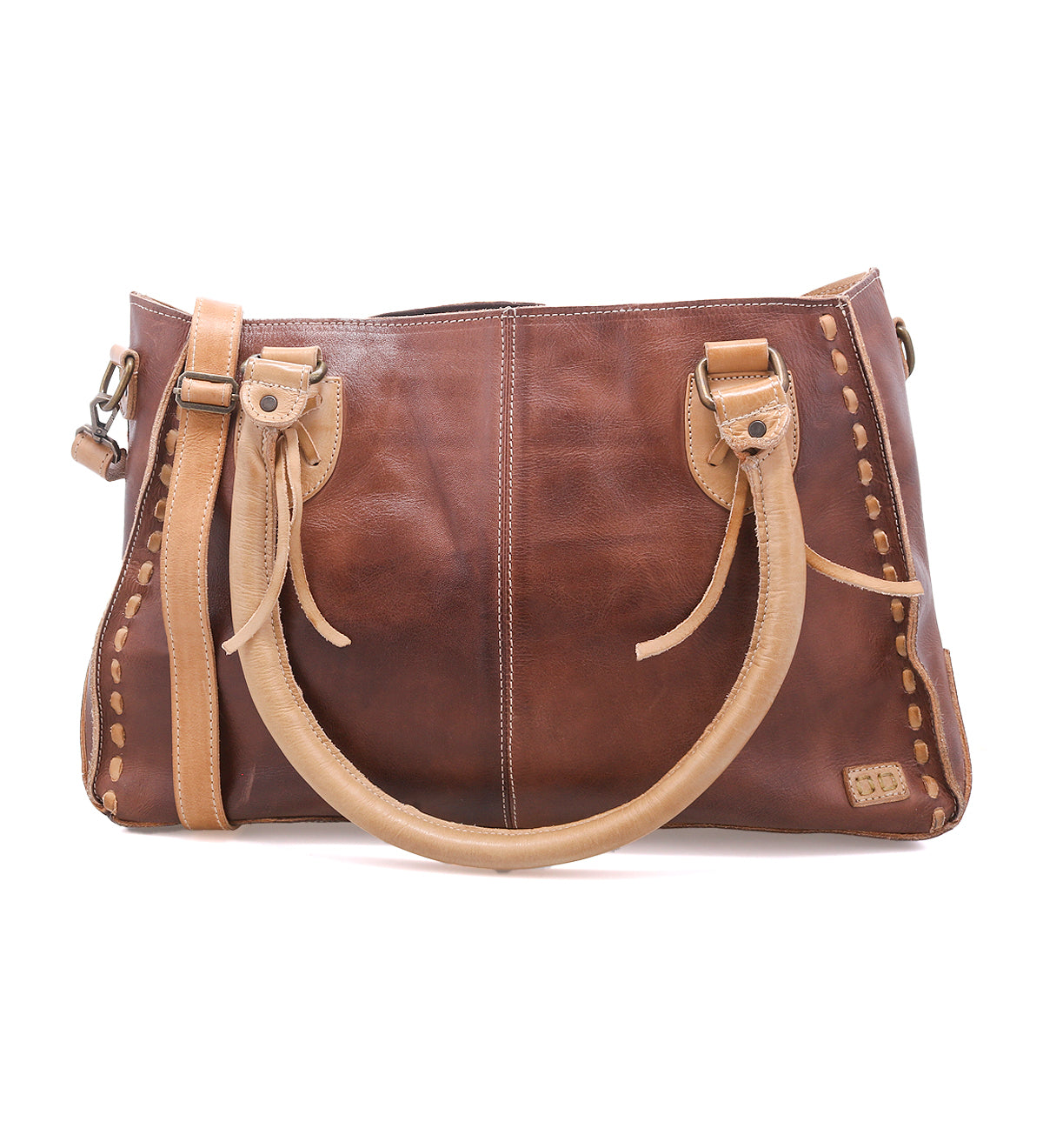 The Bed|Stü Rockababy is a compact brown leather handbag crafted from vegetable-tanned leather, featuring light tan handles and stitching, metal hardware, and a rectangular shape. The bag is photographed on a white background.