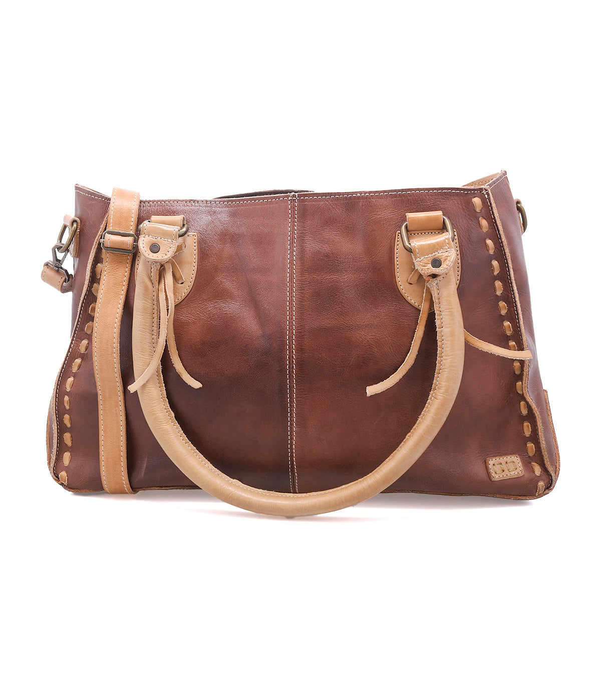 The Bed|Stü Rockababy is a compact brown leather handbag crafted from vegetable-tanned leather, featuring light tan handles and stitching, metal hardware, and a rectangular shape. The bag is photographed on a white background.