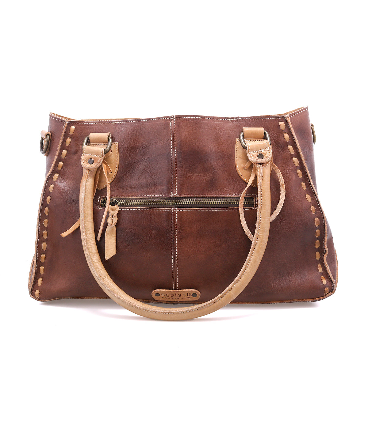 Introducing the Bed|Stü Rockababy—a brown handbag expertly crafted from luxurious vegetable-tanned leather. This compact bag features tan handles, a front zipper pocket, and decorative stitching along the edges, shown here against a white background.
