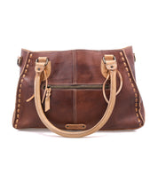 Introducing the Bed|Stü Rockababy—a brown handbag expertly crafted from luxurious vegetable-tanned leather. This compact bag features tan handles, a front zipper pocket, and decorative stitching along the edges, shown here against a white background.