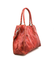 The Bed|Stü Rockaway is a large, red full-grain leather handbag featuring double handles, metal hardware, and decorative stitching, displayed at an angle against a white background.