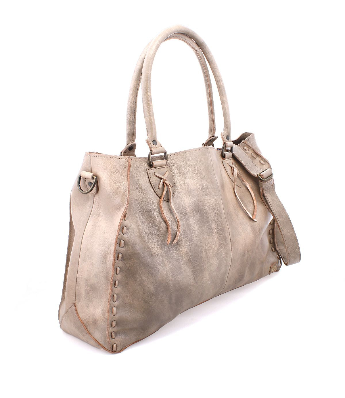 The Bed|Stü Rockaway is a taupe full-grain leather handbag featuring dual handles, a side strap, decorative stitching, and metal hardware. Designed for everyday function, it is showcased against a white background.