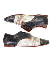 Step out in style with the Bed|Stü Rumba II — a pair of two-tone lace-up leather shoes featuring striking black and white panels, distinctive red soles, and intentional distressing for a vintage-inspired charm. Shown in side view facing opposite directions, these shoes effortlessly blend comfort and timeless appeal.