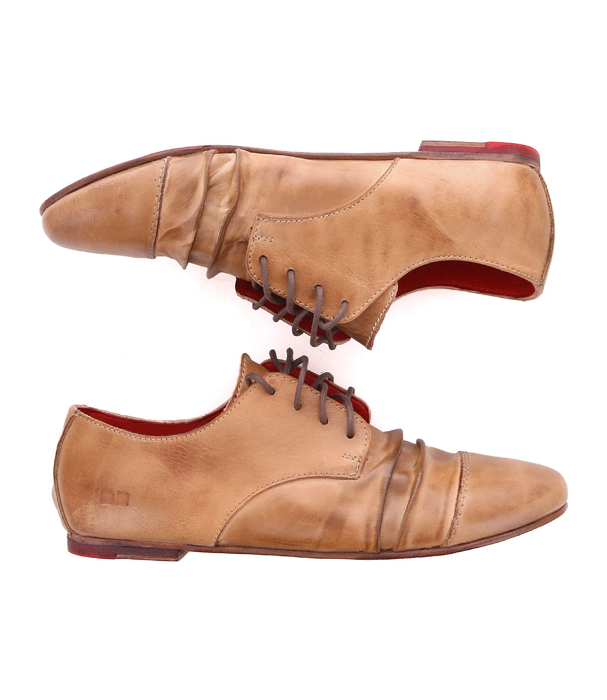 The Bed|Stü Rumba II is a pair of tan lace-up leather shoes featuring brown laces and striking red soles, shown from the side on a white background—perfect for adding stylish comfort to any occasion.