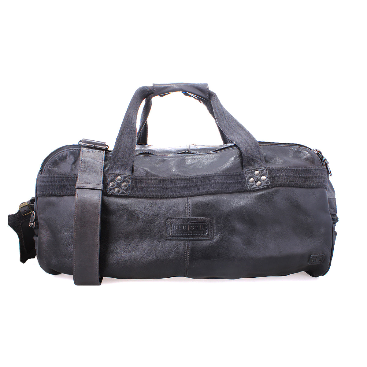 The Bed|Stü Ruslan is a black leather duffel bag featuring two handles, sturdy canvas straps, a detachable shoulder strap, and a front zipper pocket. The brand logo appears on the front, making it the ideal travel companion for any adventure.