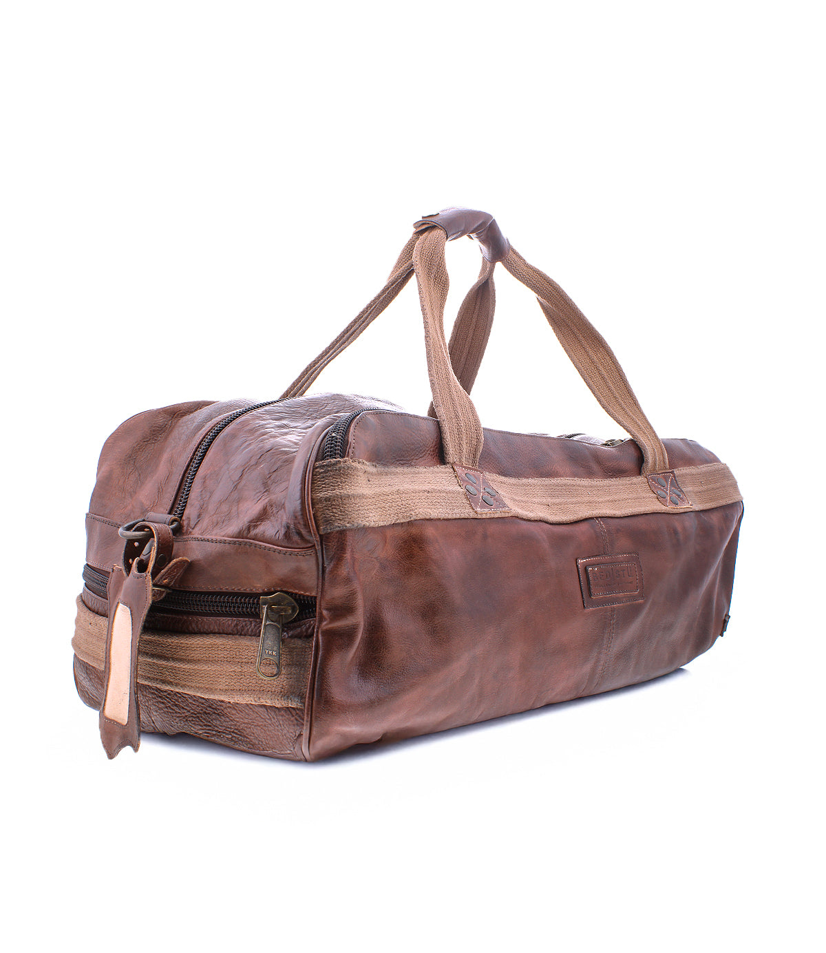 Introducing the Ruslan by Bed|Stü—a brown leather duffel bag featuring durable canvas straps, a side zipper pocket, and distinct visible stitching. Photographed on a white background, this travel bag is the perfect companion for your next adventure.