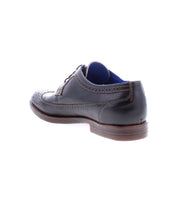 The Sandro II dress shoe by Bed|Stü is shown from the back, featuring black handcrafted leather with wingtip broguing, a brown wooden sole, and a blue inner lining.