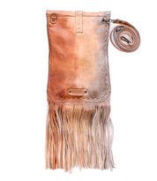 The Sandy Lane II by Bed|Stü is a handmade brown vegetable-tanned leather crossbody bag, featuring long fringe, metal studs, and an adjustable strap coiled beside it, displayed against a white background.