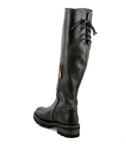 The Bed|Stü Scope boot is a black, knee-high leather style crafted from vegetable-tanned leather, featuring a side zipper, lace-up back detailing, and a thick treaded sole. Shown from a rear-side angle.