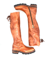 Introducing the Scope boots by Bed|Stü—a pair of tall boots expertly crafted from supple, vegetable-tanned leather, featuring convenient side zippers and distinctive lace-up backs. Shown on a white background, one boot stands upright while the other lies flat to highlight their unique design details.