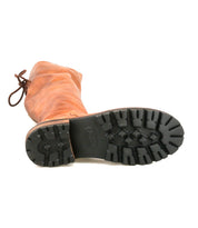 Bed|Stü’s Scope work boot, crafted from brown vegetable-tanned leather, is pictured lying on its side to display the deep, rugged lugs of its black rubber tread sole and the prominent logo at the center.