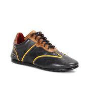 Introducing the Scurry by Bed|Stü: a retro-inspired sneaker crafted from black and brown vegetable-tanned leather with yellow accents, featuring black laces, a thin black sole, and a low-cut design built for everyday durability. Shown here photographed on a white background.