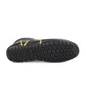 The image displays the bottom view of Bed|Stü's Scurry sneaker—a black, retro-inspired shoe featuring a hexagonal tread pattern and yellow accents, crafted for everyday durability.
