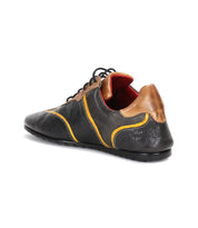 Introducing the Bed|Stü Scurry—a black and brown casual sneaker with yellow accents, red lining, and black laces. Showcased from the back and side, this retro-inspired shoe is crafted for everyday durability, blending classic style with comfortable wear.