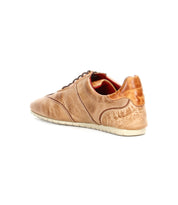 The Bed|Stü Scurry is a tan leather casual shoe, crafted from durable vegetable-tanned leather with textured detailing, visible stitching, and a contrasting white sole. Shown from a rear side angle against a white background.